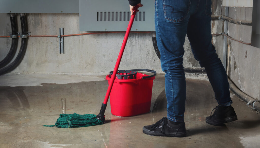 Homeowner mopping their basement floor after sewage backup